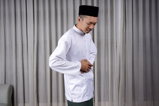 Muslim Asian man touching his stomach with in pain expression. Diseases of the gastrointestinal tract that often cause abdominal pain, such as appendicitis, enteritis