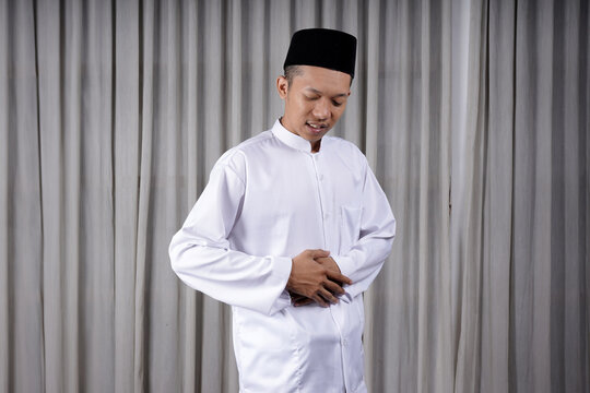 Muslim Asian man touching his stomach with in pain expression. Diseases of the gastrointestinal tract that often cause abdominal pain, such as appendicitis, enteritis