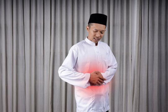 Muslim Asian man touching his stomach with in pain expression. Diseases of the gastrointestinal tract that often cause abdominal pain, such as appendicitis, enteritis