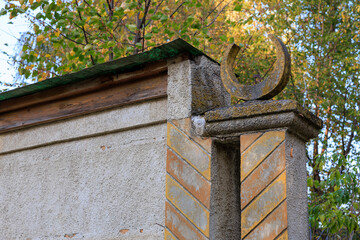A stone wall with a green roof and a large, curved, pointed object on top