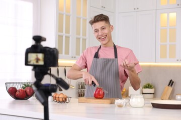 Fototapeta na wymiar Smiling food blogger cooking while recording video in kitchen