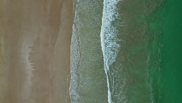 Aerial view of sea waves breaking on sand tropical beach, slow motion, 4k