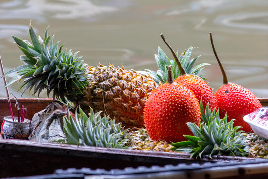 Pineapple (Ananas comosus)  and Gac (Momordica cochinchinesis) for sale on floating market, Ampawa, Thailand