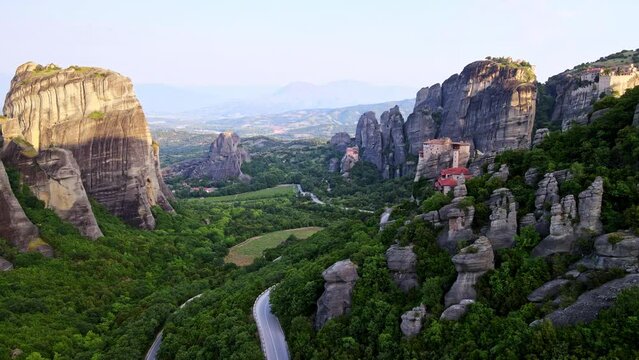 Flying over Meteora Monasteries at sunrise, Greece. Landscape scenery with green hills, rocks, and old Monasteries