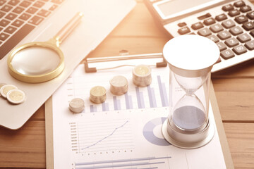 Coins, hourglasses, laptops, and calculators placed on financial data reports