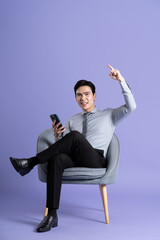 Portrait of Asian business man sitting on sofa, isolated on purple background