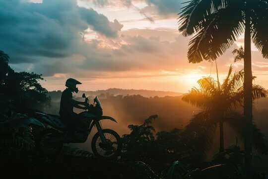 Dirt biker enjoying a tropical sunset - An evocative scene of a dirt biker pausing to enjoy the beauty of a tropical sunset and lush landscape