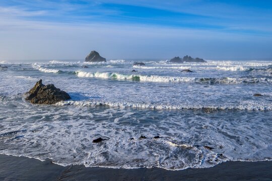Sea stacks with foamy waves at sand beach. Bandon Beach in the morning.  Oregon. USA