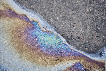 Color gasoline fuel spot on black asphalt, industrial pollution concept.
