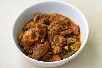 Delicious beef curry in a bowl on wooden background. Beef bhuna is a popular, flavorful, and spicy Bangladeshi dish. It is great food for eating with rice or bread.
