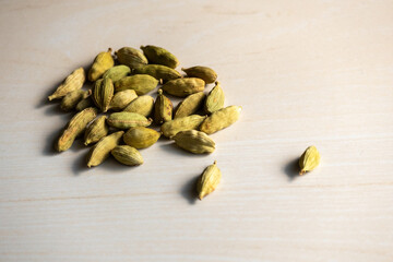 A heap of cardamom isolated on a wooden background. Its scientific name is Elettaria cardamomum and locally in Bangladesh, it is called Elachi. 