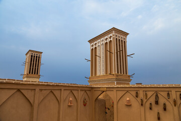 A wind catching tower or ventilation tower made of adobes in Yazd, Iran with a cloudy sky in the background