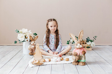 Little girl playing with Easter toy bunnies and a basket of Easter eggs. Child celebrating Easter....