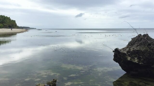 There are some big rocks in the water at the end of Solangon beach in Siquijor Island. Its an overcast day on the beach in the Philippines. The beautiful landscape in Siquijor.
