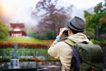 Traveller man or blogger using professional DSLR mirrorless camera take photo landscape autumn view of Katsuoji Temple, Osaka city, Japan.- Travel or tourism concept.