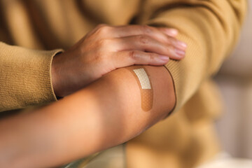Closeup image of a woman with adhesive bandage, medical plaster, band aid on her arm