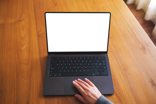 Top view mockup image of a woman working on laptop computer with blank screen on wooden table