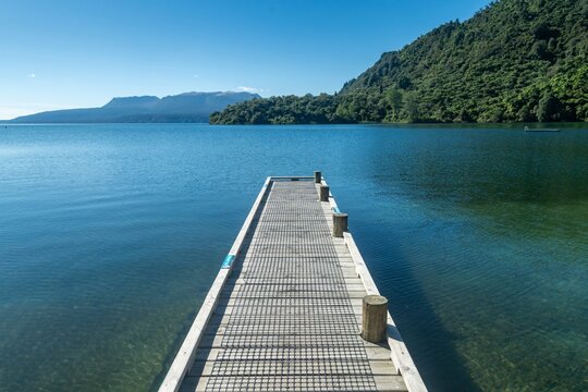 Pier leading into calm lake. Lake Tarawera, Rotorua, Bay of Plenty, New Zealand.