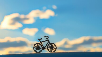 Fototapeta na wymiar Bicycle toy shadow on silhouette, lovely bright sky as background, international bicycle day