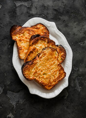 Slice of crispy baked homemade brioche french toast on a dark background, top view