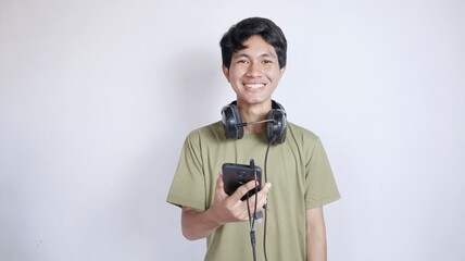 Obraz premium happy asian man using earphones and holding mobile phone