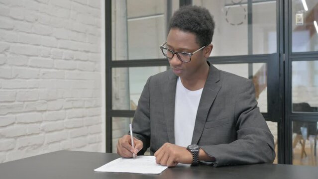 Young African Man Working on Documents in Office