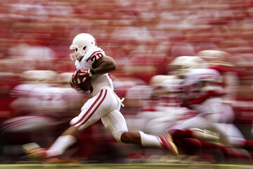 A dynamic action shot of a college football game, capturing a pivotal play with blurred motion, leaving room in the foreground for insights on the game's outcome or player achievements