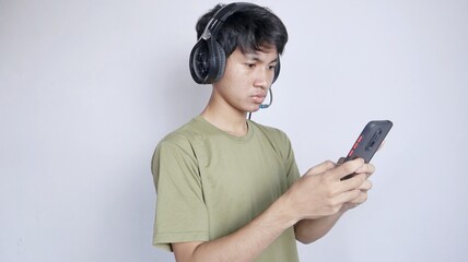 serious asian man using earphones and playing smartphone