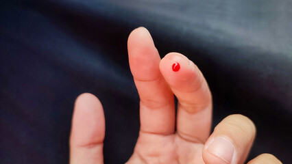 A drop of blood on the fingertip due to a needle prick to check uric acid, sugar levels, hemoglobin and cholesterol.