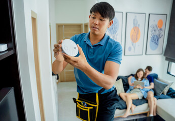 Obraz premium Technician installing fire safety detector in a modern apartment
