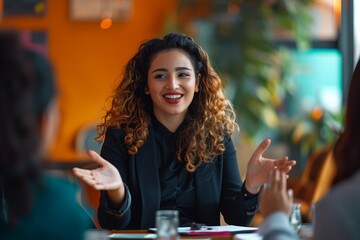 Smiling woman with curly hair having a conversation at a cafe, with warm, vibrant background.