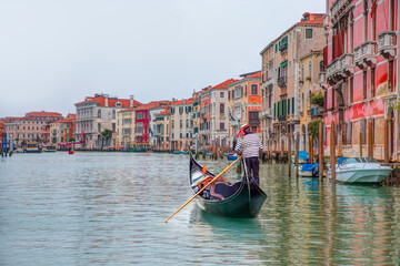 Venetian gondolier punting gondola through grand canal waters of Venice Italy