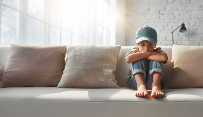 Junge Teenager sitzt allein einsam traurig in sich gekehrt barfu&szlig; auf vor Couch im Wohnzimmer einsam voller Gef&uuml;hle Emotionen und isoliert sich ungl&uuml;cklich Trauer Angst Mobbing