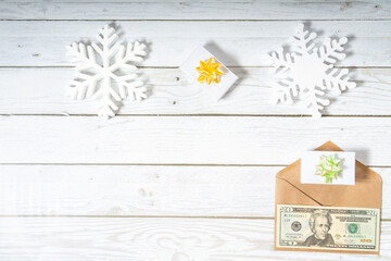 American dollars banknotes in the envelope with giftbox on a wooden white table. Topview Christmas background with snowflakes and copyspace	
