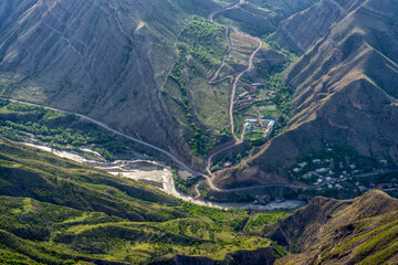 Picturesque mountain spring landscape at sunset. Amazing scenery with mountain valley and river in sunlight. Village Khebda, view from Goor, Dagestan republic, Russia. Beauty of nature, Caucasus