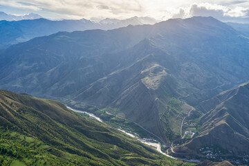 Picturesque mountain spring landscape at sunset. Green mountainside against amazing scenery with mountain ridge and river in sunlight. Goor, Dagestan republic, Russia. Beauty of nature, Caucasus