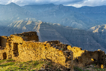 Old ruined aul against amazing landscape with mountain slope at sunset. Ancient caucasian village...
