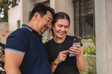 Southeast Asian couple enjoying social media on a phone outdoors