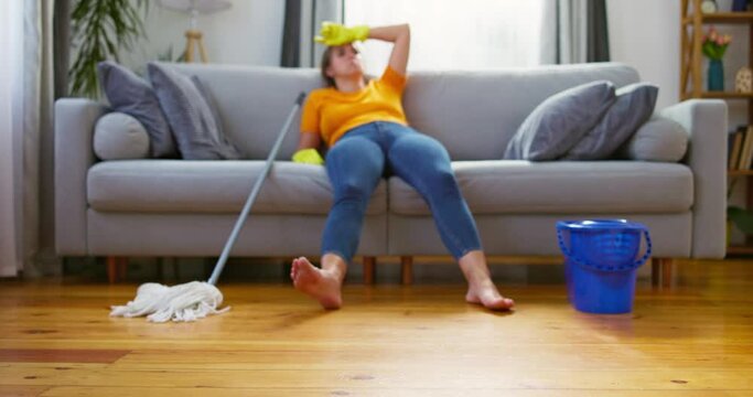 Woman resting on couch after mopping floor. 
