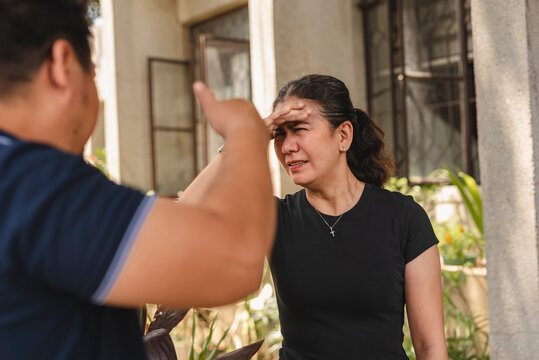 Frustrated middle-aged Asian woman by her husband's complaints outside their house