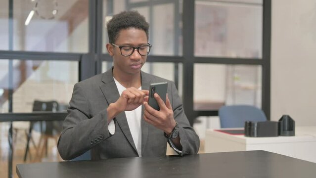 African American Man Typing Message on Phone in Office