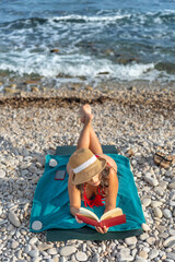 Young girl reading a book on the beach