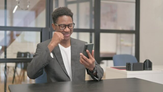African American Man Celebrating Success on Phone in Office