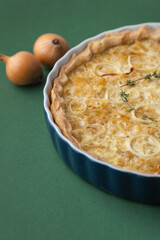 Homemade onion cake on the green background. Traditional quiche pie with steamed onions, cheese and bacon