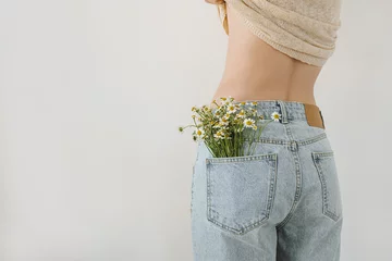 Velvet curtains Graffiti collage Backside view of young pretty woman. Chamomile flowers bouquet in jeans pocket