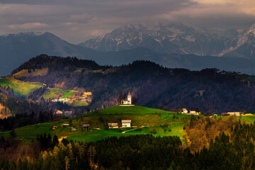 A scenic church of saint Thomas in Slovenia with the devil light patterns. A church on top of a...