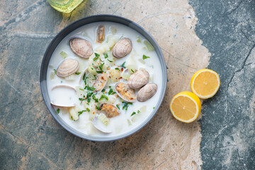 Plate with new england clam chowder on a beige and grey granite background, horizontal shot, top view