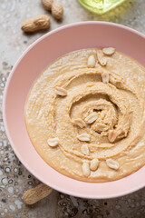 Roseate bowl with peanut butter or paste made from ground, dry-roasted peanuts, vertical shot, middle close-up