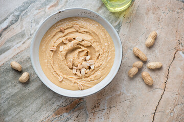 Bowl of freshly made peanut butter on a grey and beige granite background, horizontal shot, top view