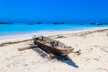 Old wooden boat ashore on tropical sandy Nungwi beach in the Indian ocean on Zanzibar, Tanzania